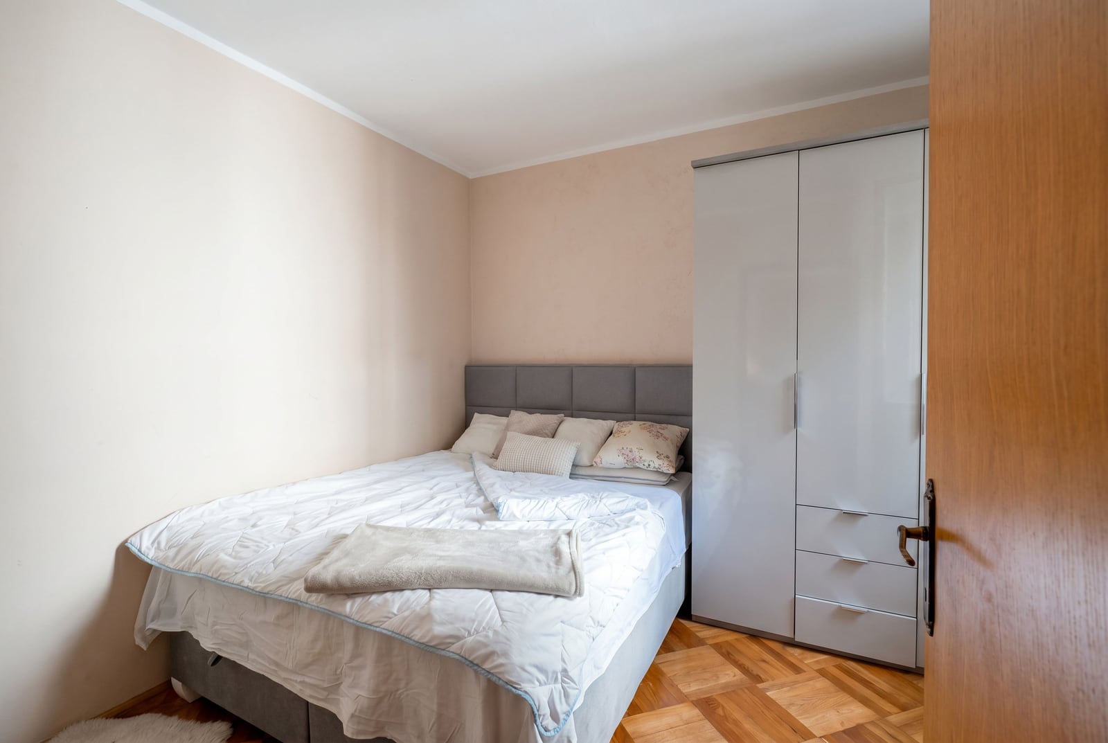 Cozy bedroom with a double bed and a light-colored wardrobe in an apartment for sale, Budva, Montenegro.