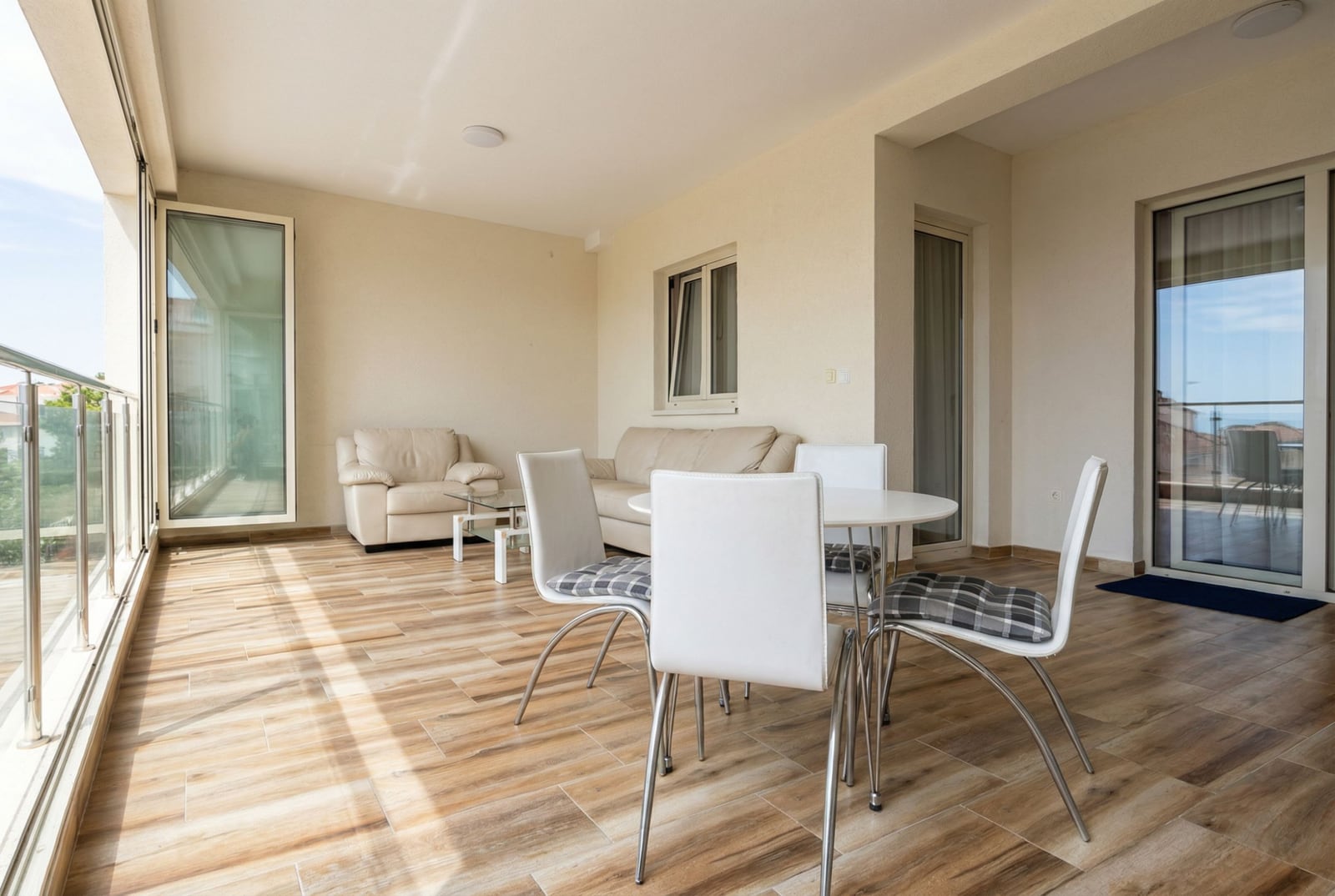 Spacious terrace with a dining area and soft seating in an apartment in Pržno, Montenegro, with panoramic glazing.