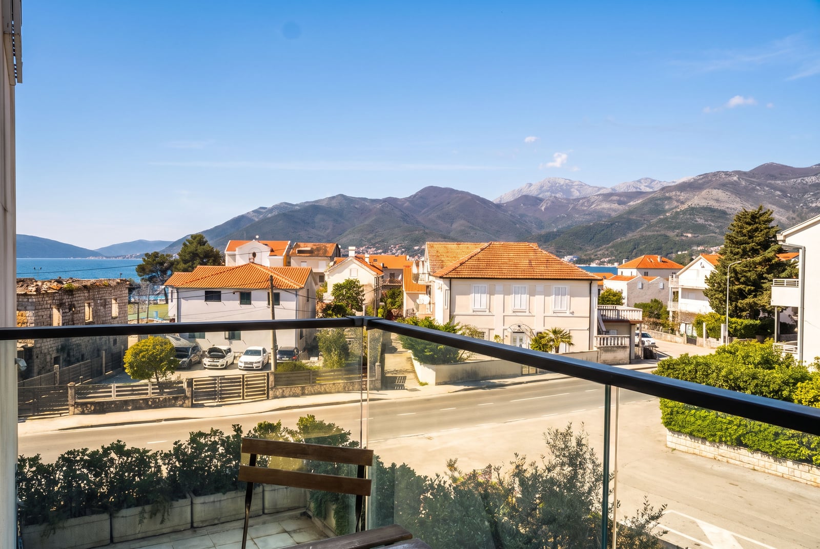 View from the apartment balcony in Tivat, Montenegro: panorama of the mountains, sea, and the city's tiled rooftops