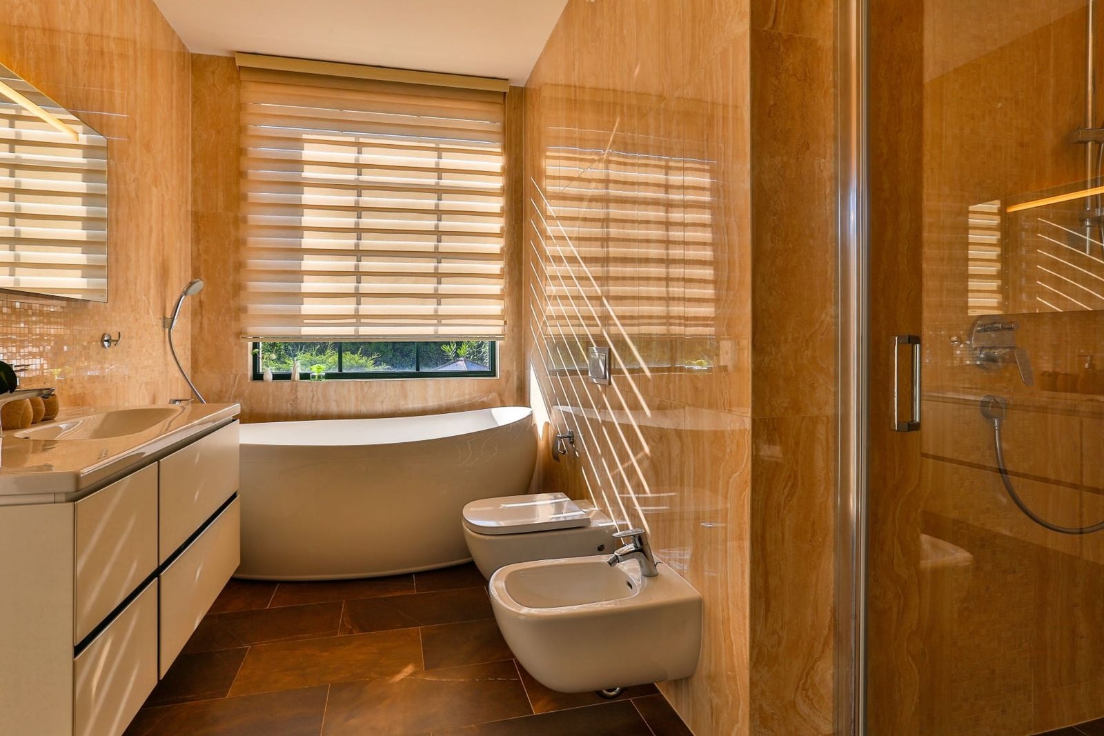 Modern bathroom with beige stone finish, bathtub, and shower in a villa in Tivat, Montenegro.