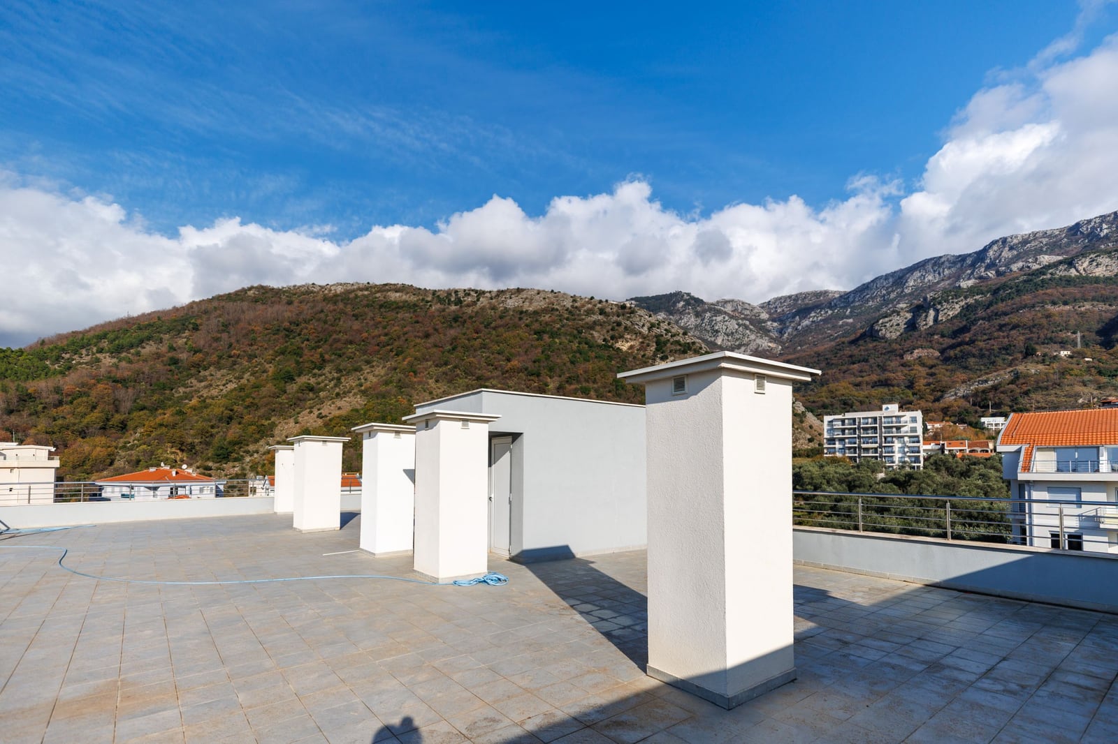 Open penthouse terrace in Bečići, Montenegro, with mountain views and modern tile flooring.