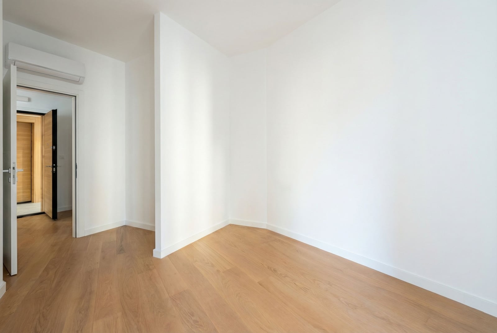 Bright empty living room with parquet flooring and white walls in an apartment, Becici, Montenegro. View of the interior door.