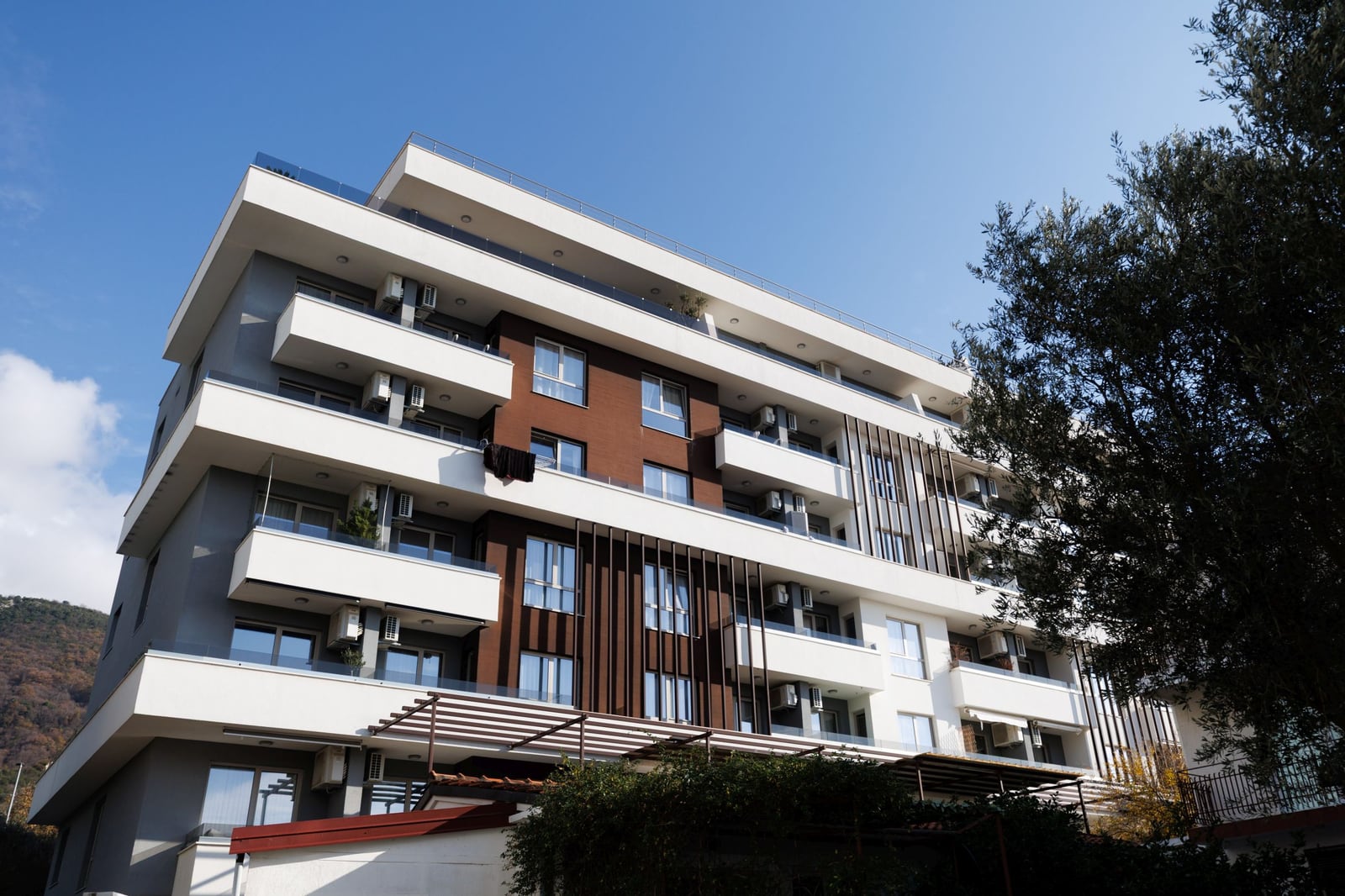 Modern apartment building with terraces in Bečići, Montenegro: facade with wood finish and panoramic windows.