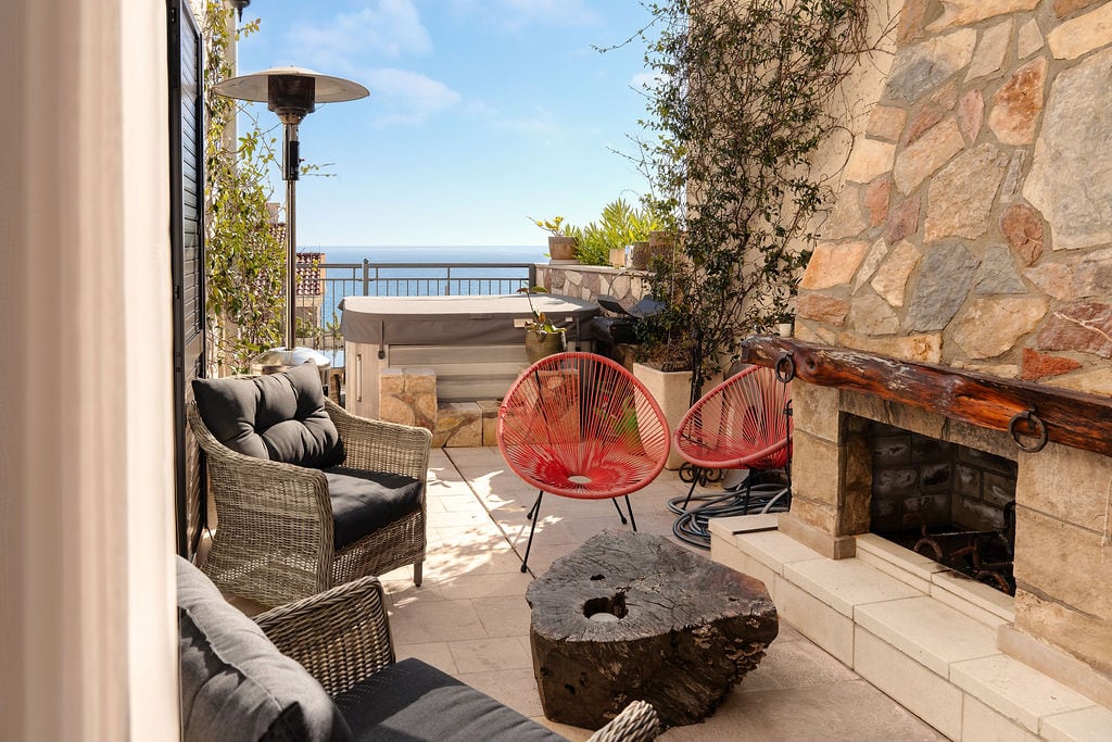 Townhouse terrace in Luštica, Montenegro: sea view, jacuzzi, stone fireplace, and designer outdoor furniture.