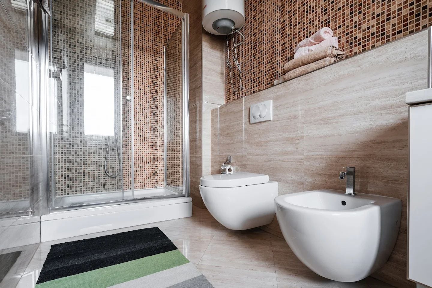 Modern bathroom in an apartment in Budva, Montenegro: shower cabin, wall-hung toilet, bidet, and mosaic tile.