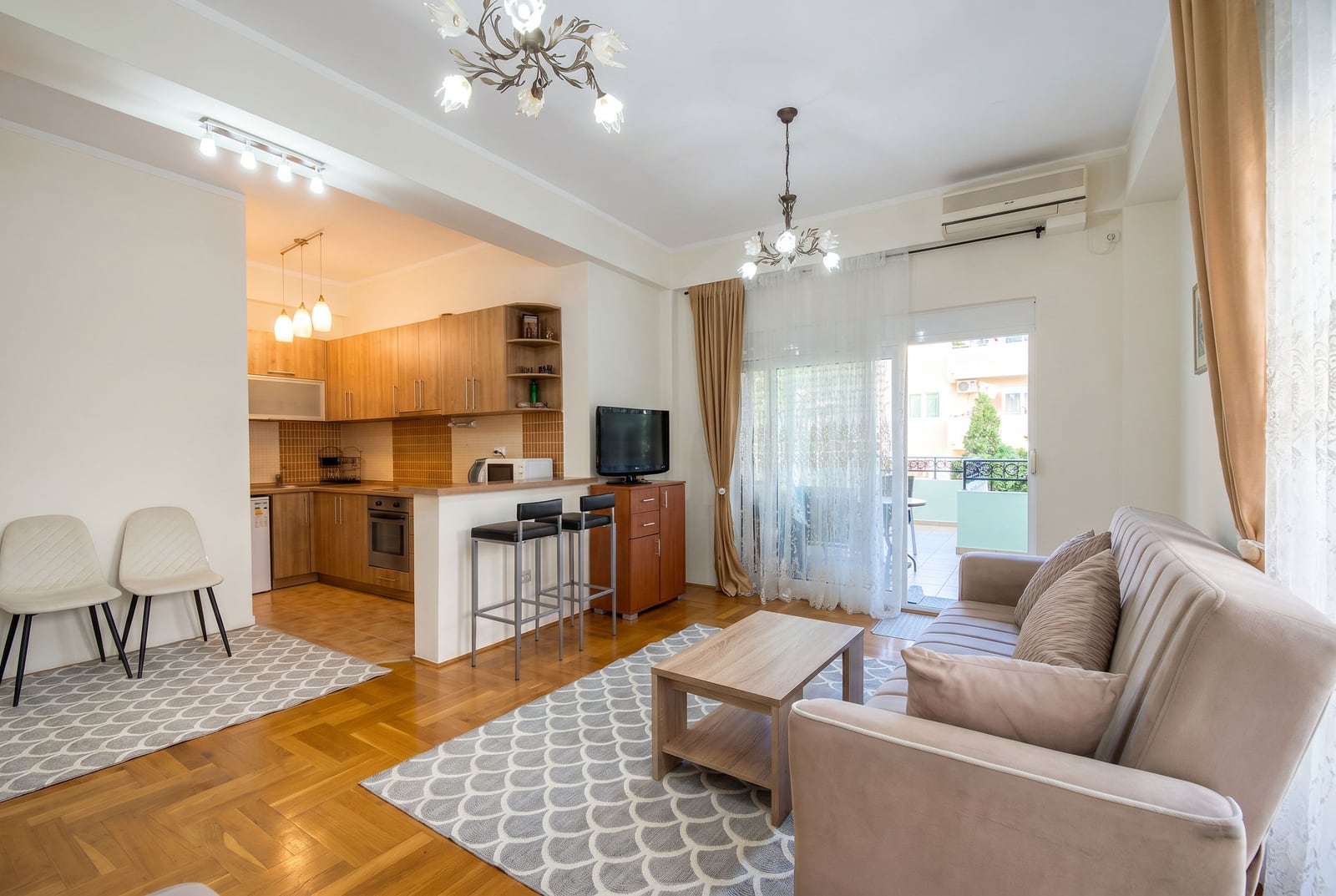 Living room with kitchen in an apartment in Budva, Montenegro: bright interior, comfortable sofa, breakfast bar, and access to the terrace.
