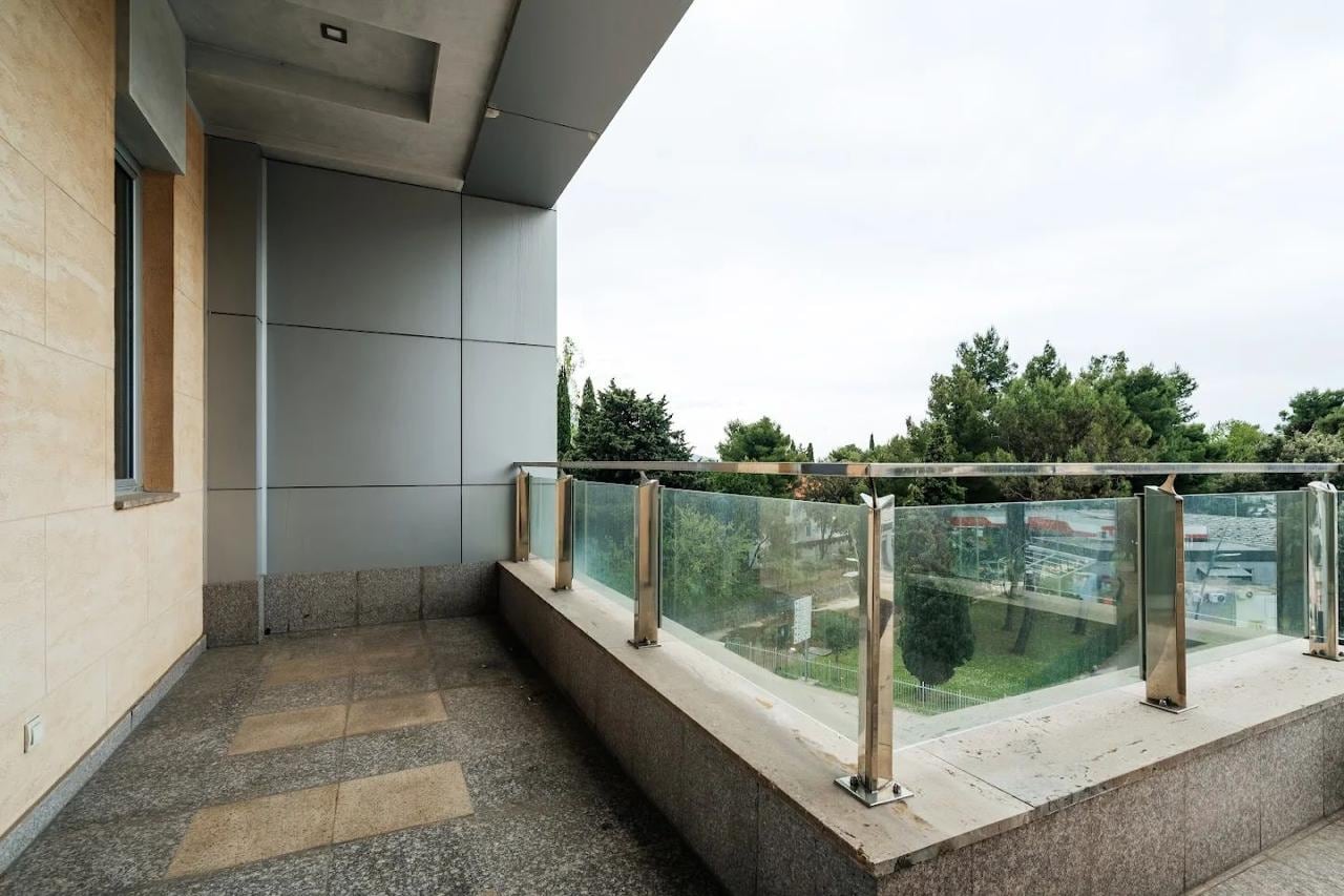 Spacious balcony with panoramic railing and a view of greenery in a modern apartment, Budva, Montenegro.