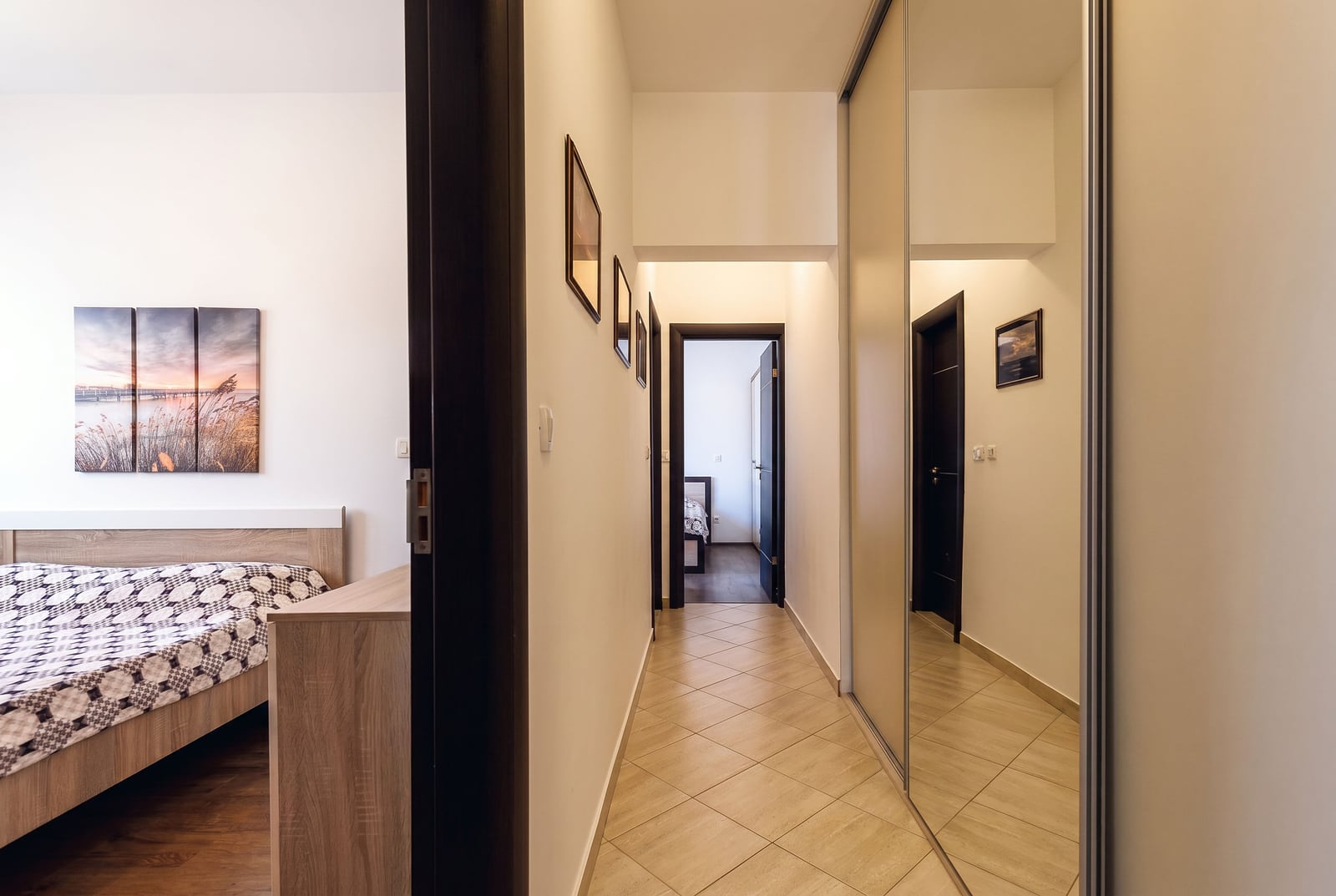Bright hallway with a mirrored wardrobe in a modern apartment in Budva, Montenegro, view of the bedroom with a bed.
