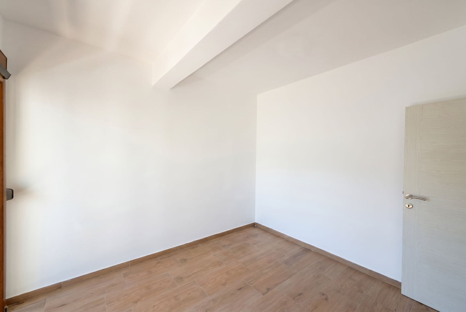 Bright empty bedroom with white walls and wooden flooring in an apartment for sale, Budva, Montenegro.