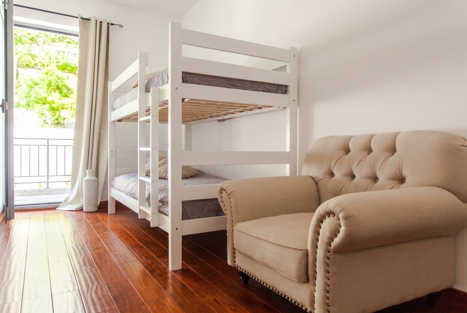 Bedroom with a bunk bed and armchair in an apartment in Risan, Montenegro: bright interior and balcony access.