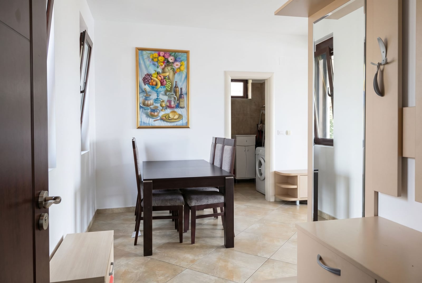 Living room with dining area in an apartment in Rafailovići, Montenegro: dark table, chairs, and light floor tiles.