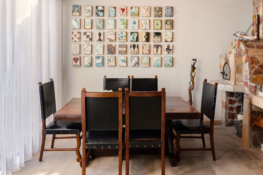 Dining area in a Luštica townhouse, Montenegro: wooden table, leather-upholstered chairs, and a stone fireplace.