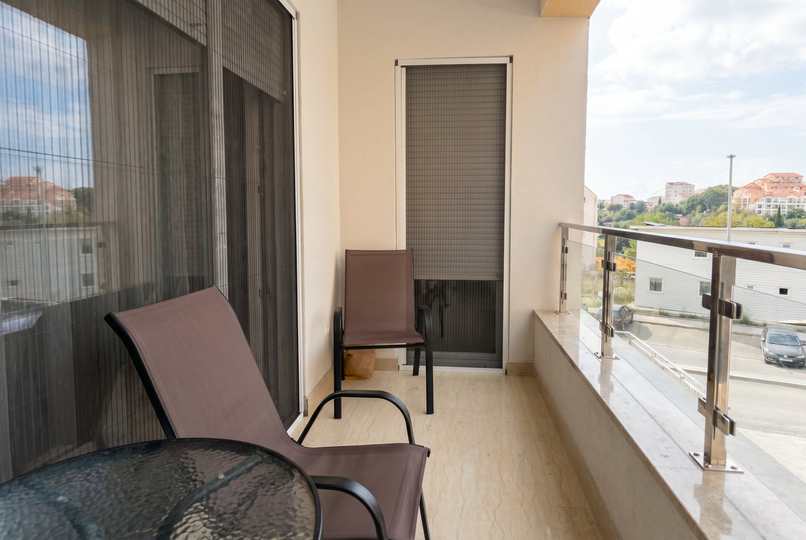 Balcony with furniture and glass railing in an apartment, Bečići, Montenegro. View of the city and mountains, modern finish.