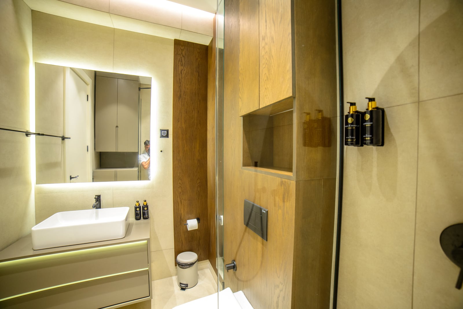 Modern bathroom in an apartment in Bečići, Montenegro: stylish finishes, wooden panels, and mirror lighting.