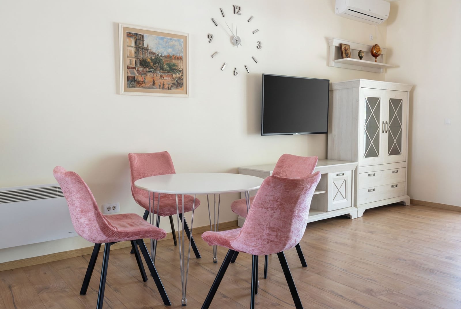 Living room in an apartment in Pržno, Montenegro: dining area with pink velvet chairs, TV, and light-colored furniture.