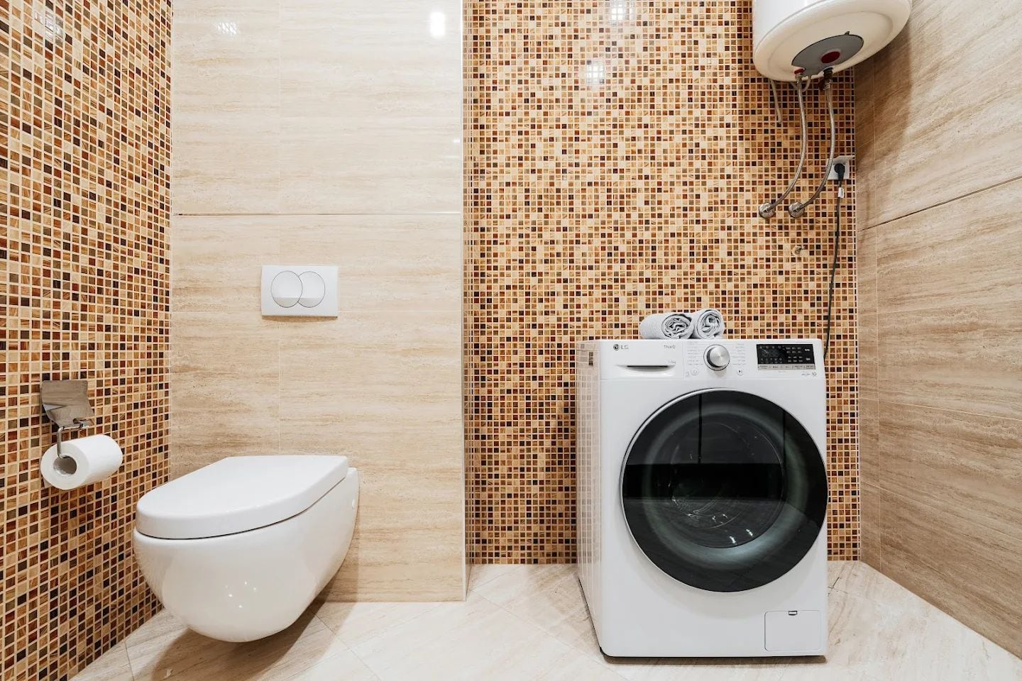 Modern bathroom in an apartment in Budva, Montenegro: wall-mounted toilet, washing machine, and mosaic tile.