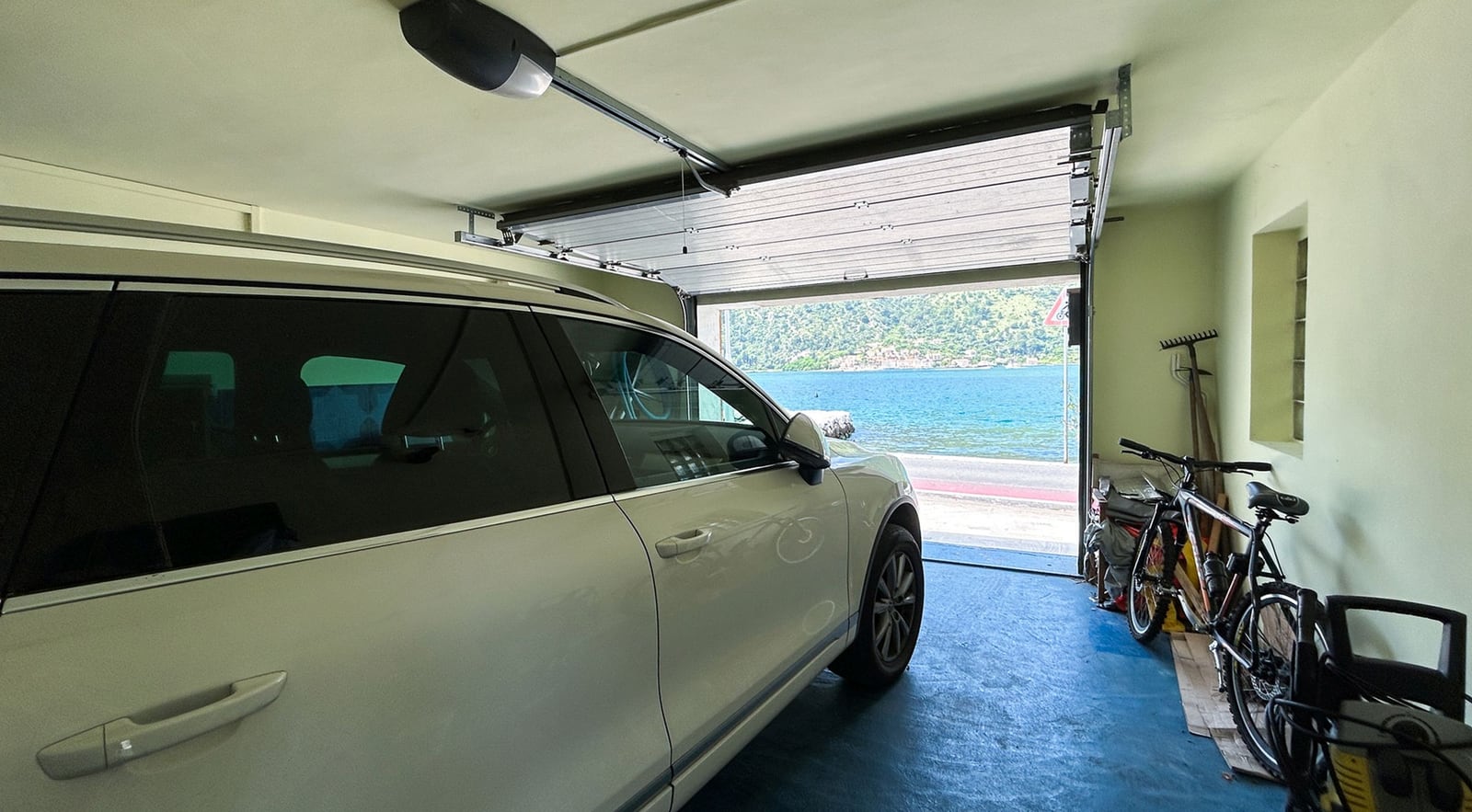 Garage with a car and sea view in a villa, Dobrota, Montenegro. Spacious room with automatic gates.