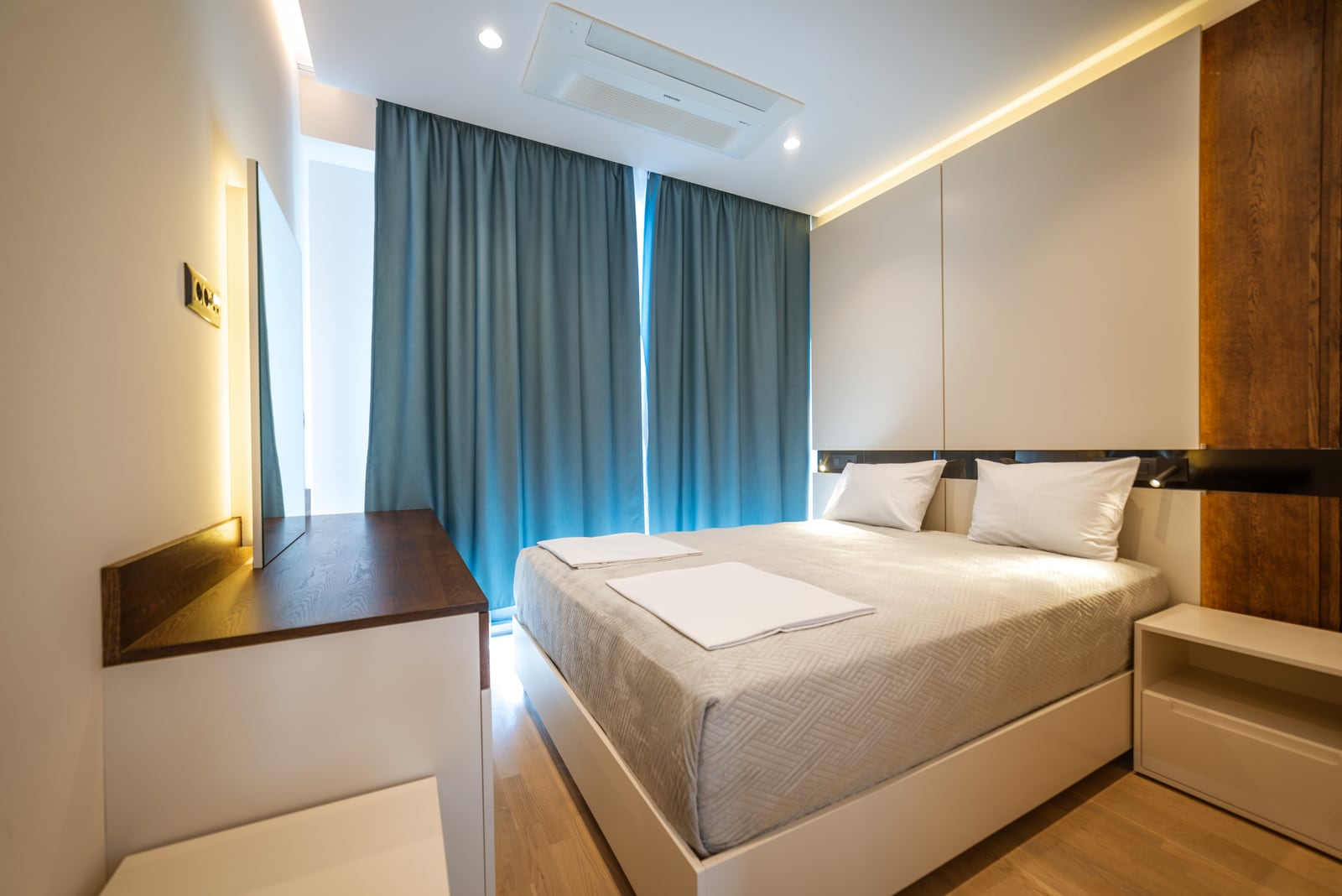 Modern bedroom with a double bed and blue curtains in an apartment in Bečići, Montenegro. Interior with accent lighting.