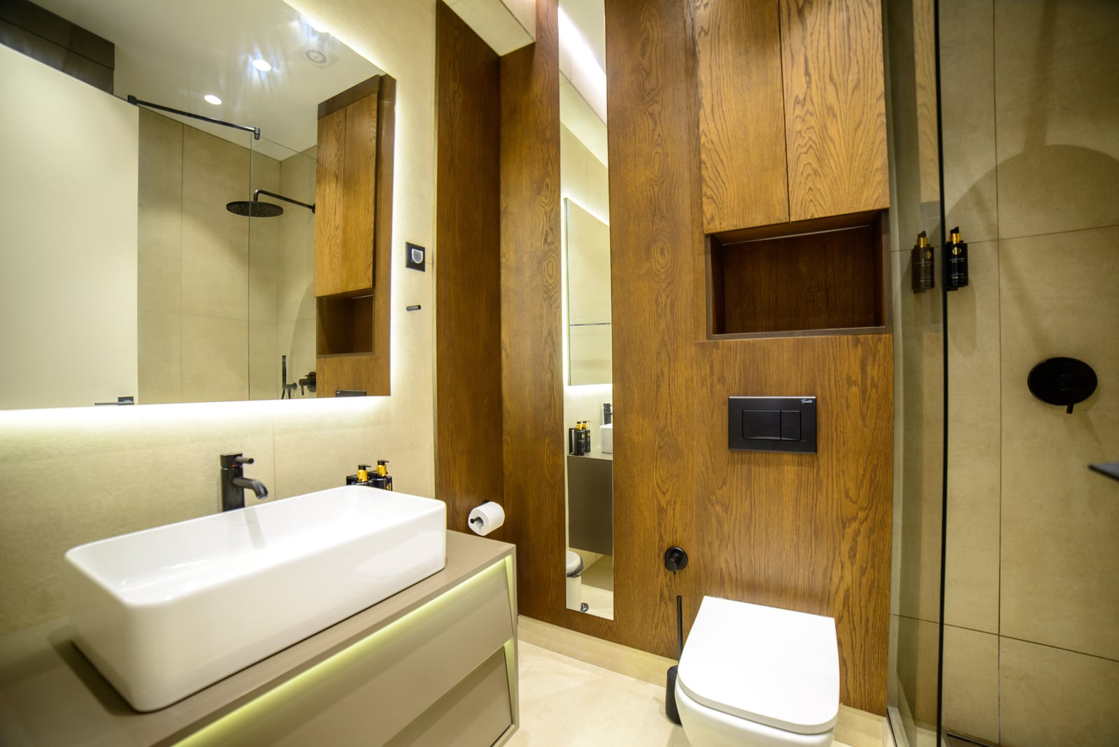 Modern bathroom with wood-like finish in an apartment in Bečići, Montenegro: shower, stylish fixtures, and lighting.