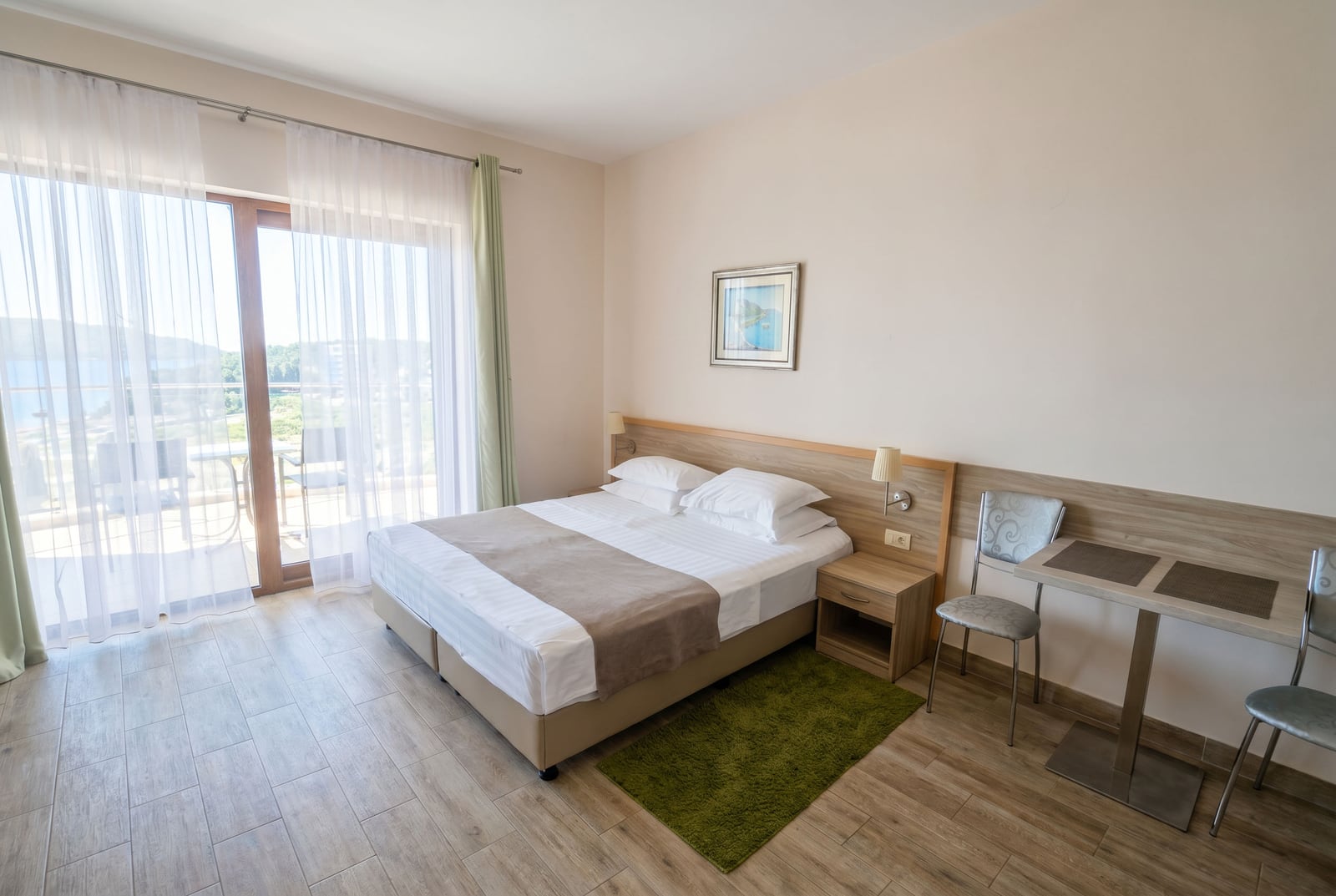 Bedroom in an apartment in Bečići, Montenegro: double bed, dining area, and a balcony with a sea view.