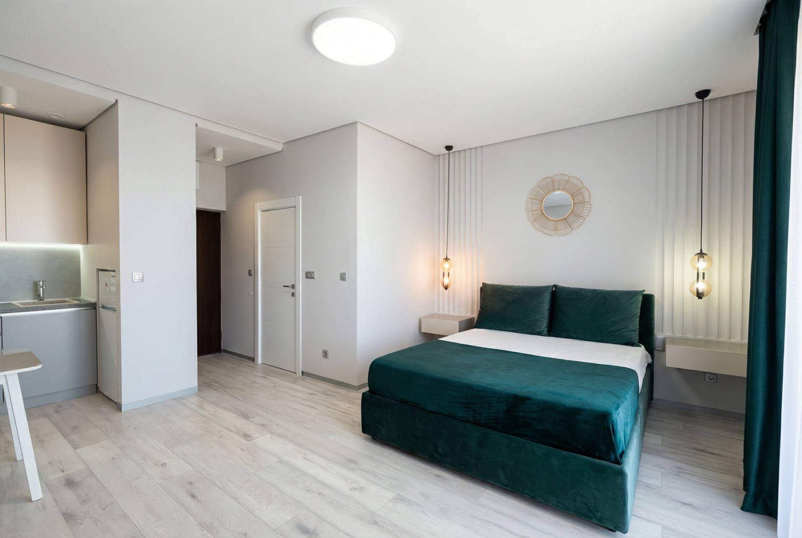 Modern bedroom with an emerald bed and kitchen in an apartment in Bečići, Montenegro: stylish interior and light flooring.