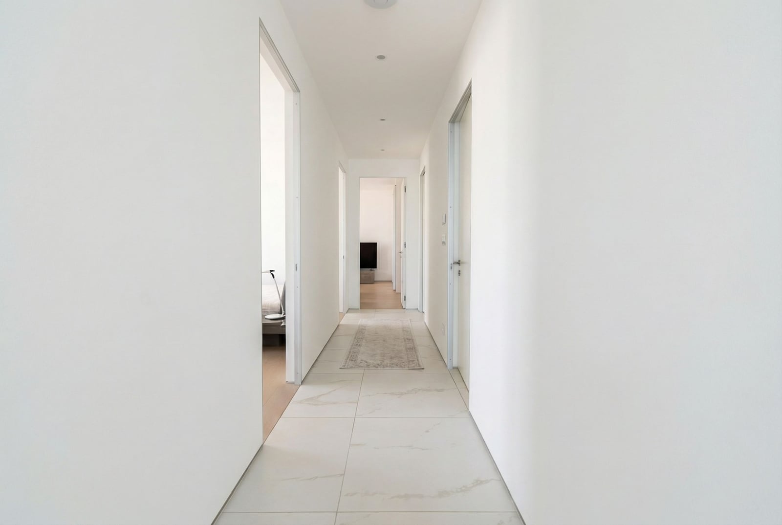 Bright hallway in a modern apartment in the Dukley complex, Budva, Montenegro: white walls and porcelain tile flooring.