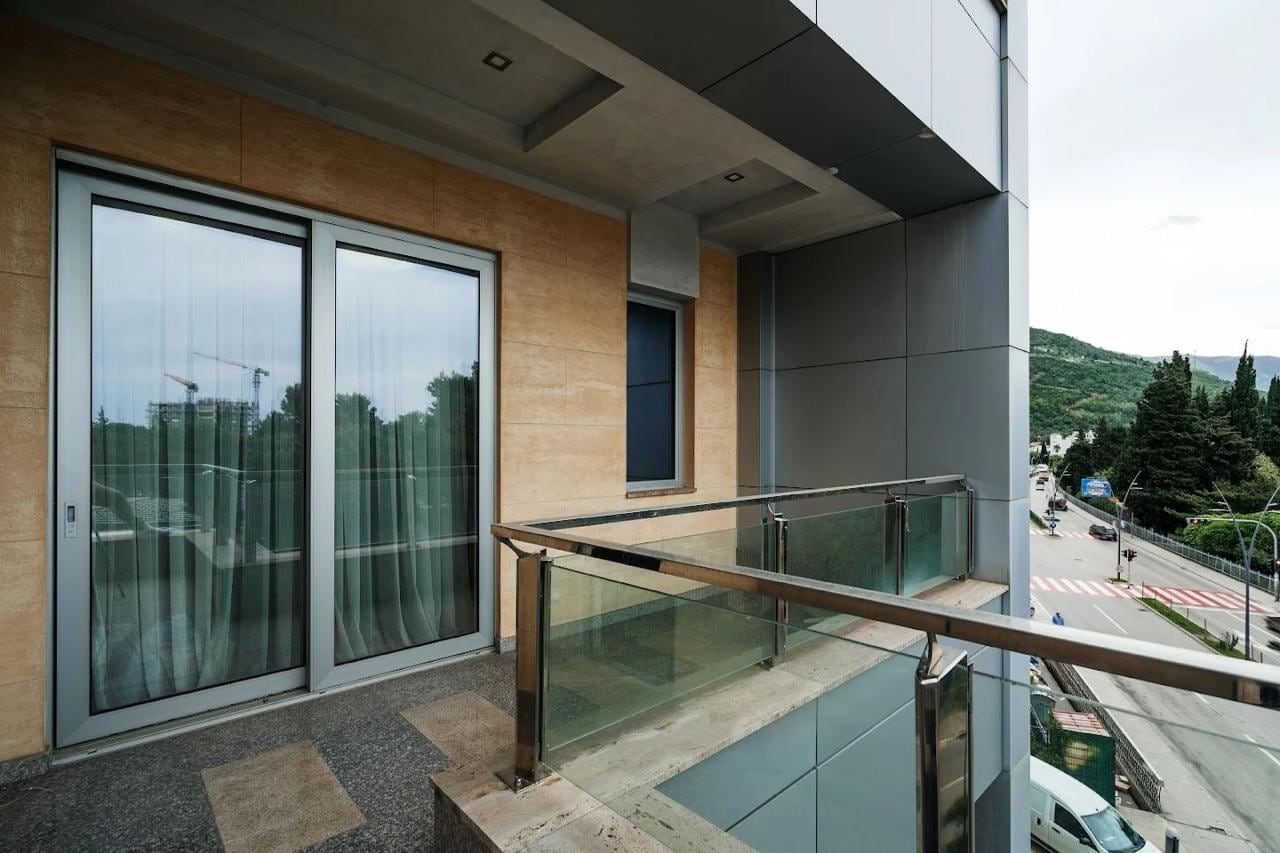 Modern balcony with panoramic glazing in an apartment, Budva, Montenegro: city and mountain views, facade finish.