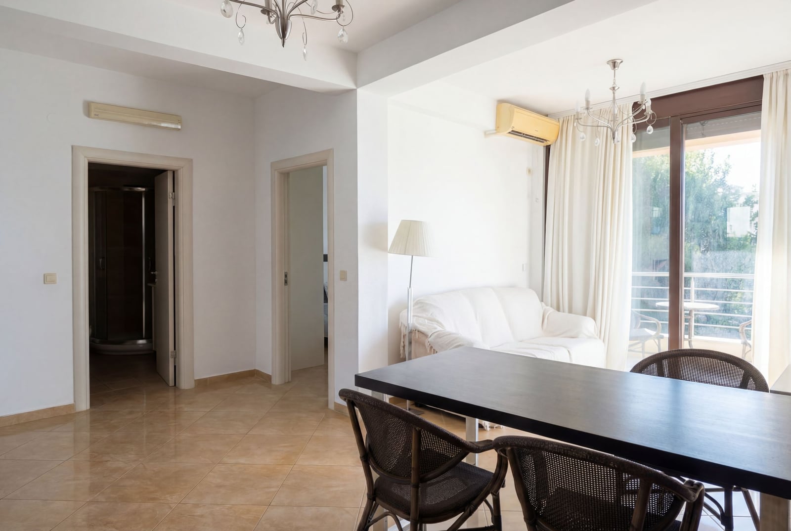 Living room with dining area in an apartment in Rafailovici, Montenegro: bright interior, terrace, and wicker chairs.