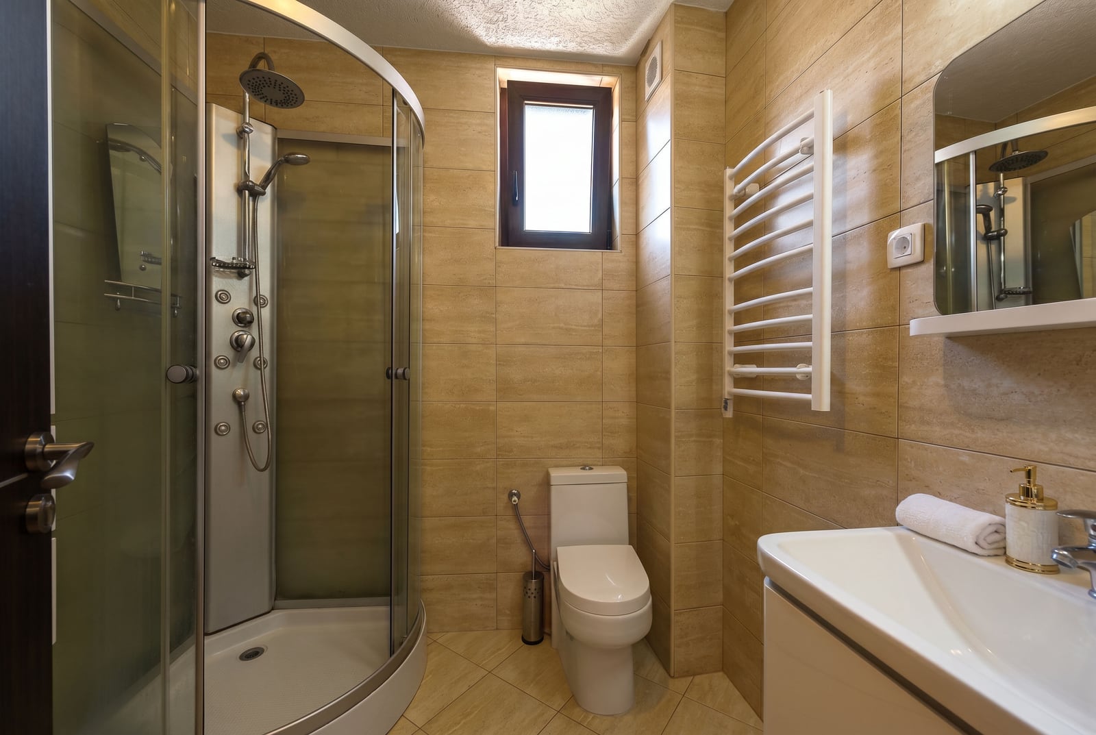 Modern bathroom in an apartment in Budva, Montenegro: shower cabin, white sanitary ware, and beige tiles.