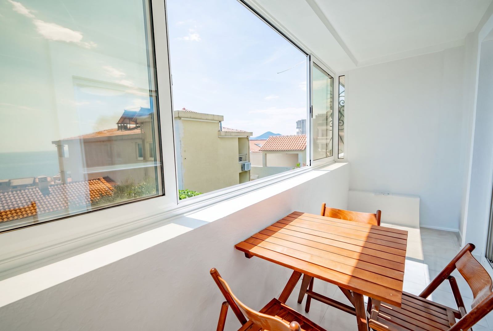 Bright balcony with wooden furniture and a sea view in an apartment, Sveti Stefan, Montenegro.