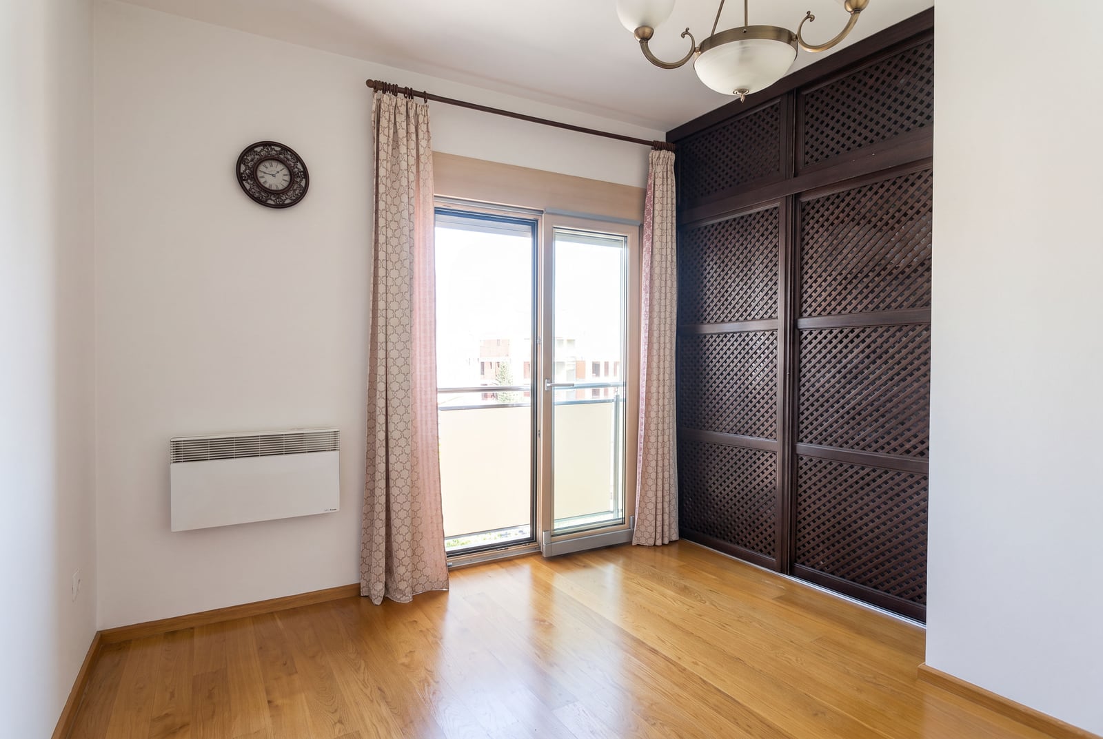 Bedroom with parquet flooring, a large dark wardrobe, and access to a balcony in an apartment in Bečići, Montenegro.