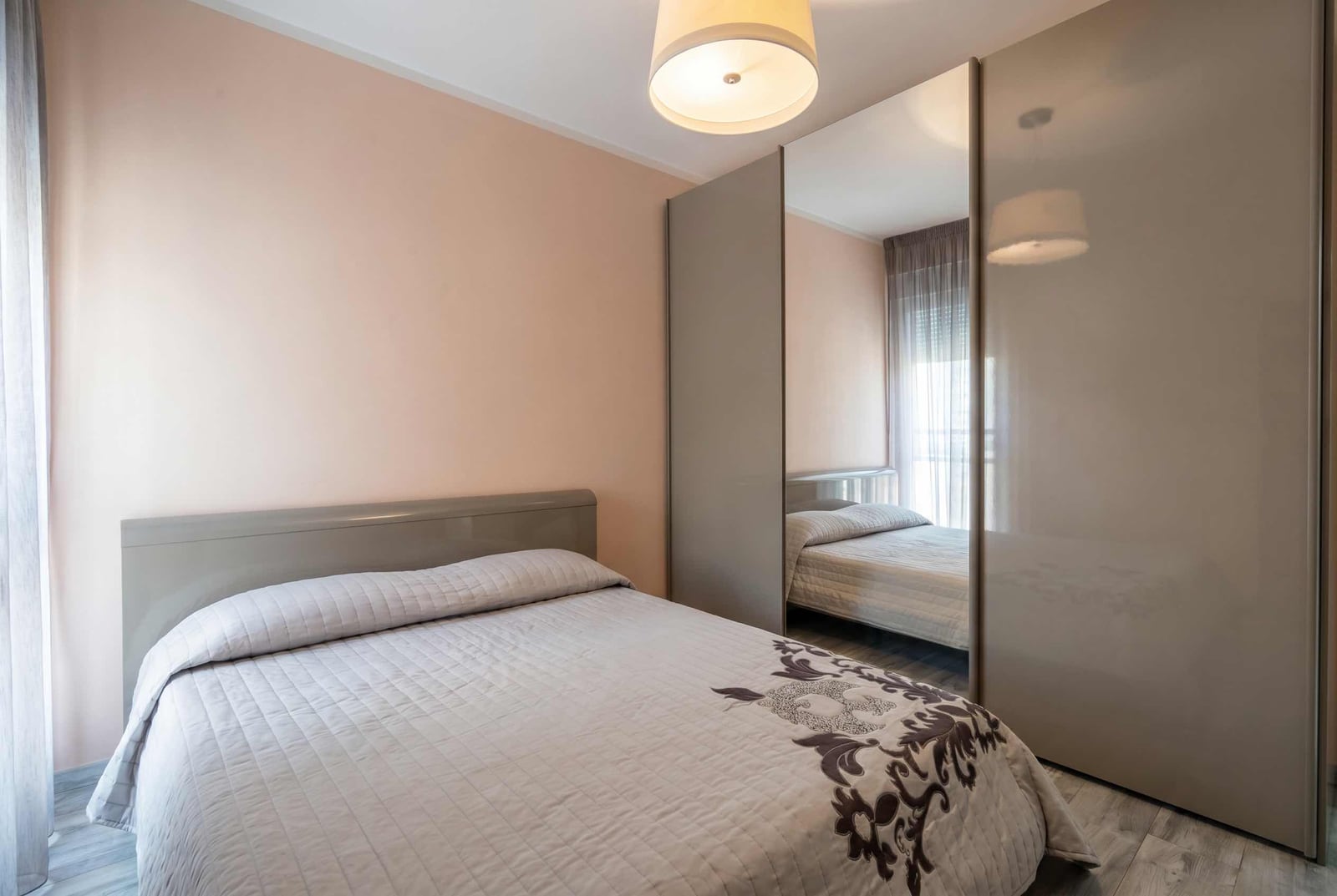 Cozy bedroom with a double bed and a mirrored sliding-door wardrobe in an apartment, Becici, Montenegro.
