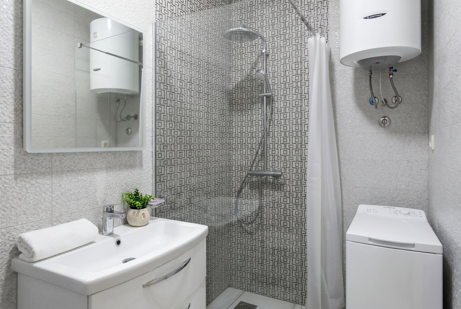 Modern bathroom in an apartment in Becici, Montenegro: walk-in shower, washing machine, and light-toned finishes.