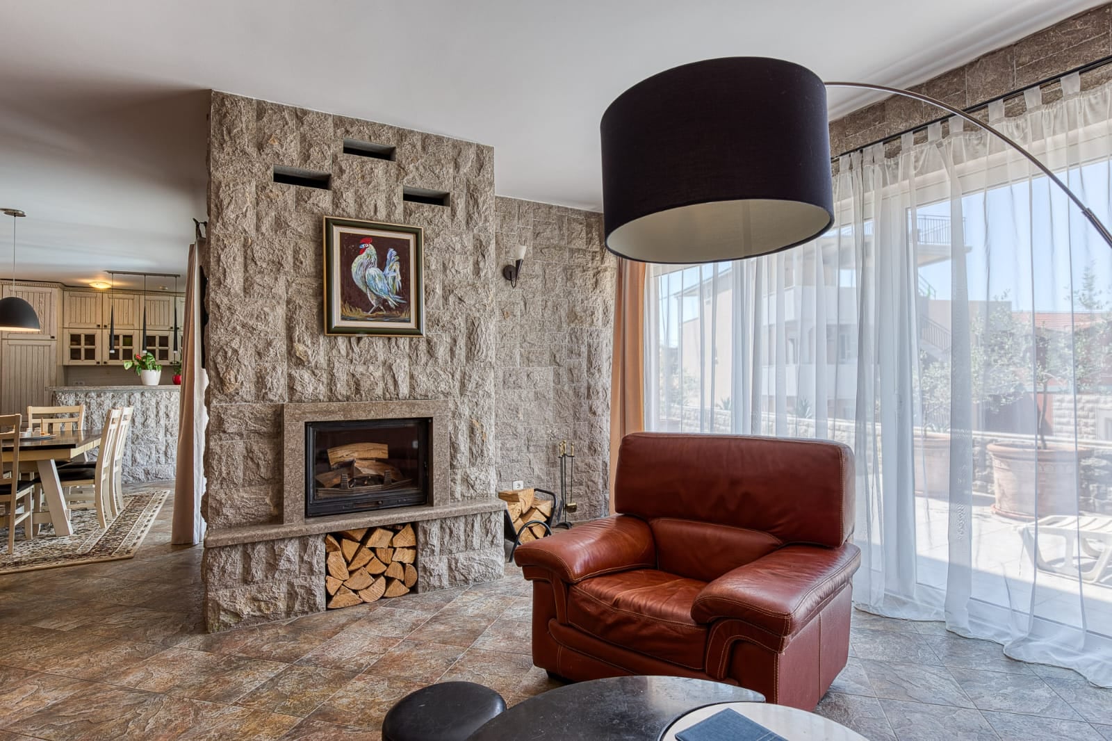 Living room with a fireplace, stone detailing, and a leather armchair in a villa in Becici, Montenegro.