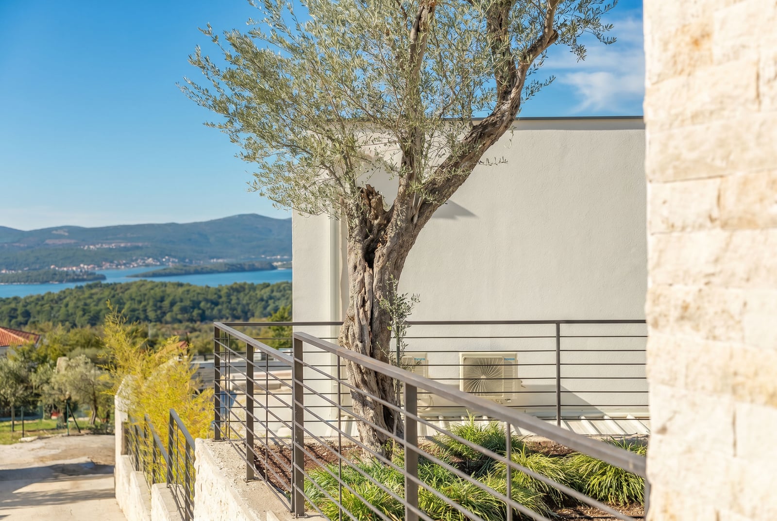 Terrace of a townhouse in Kavač, Montenegro: sea view, olive tree, and modern stone facade finish.