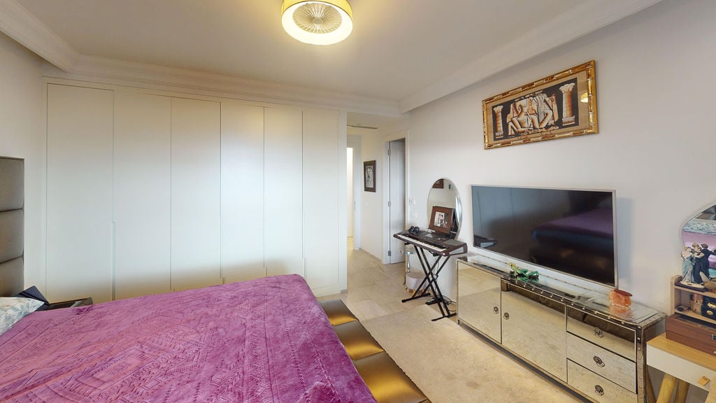 Bedroom in a townhouse, Luštica, Montenegro: built-in wardrobe, mirrored TV stand, and double bed.