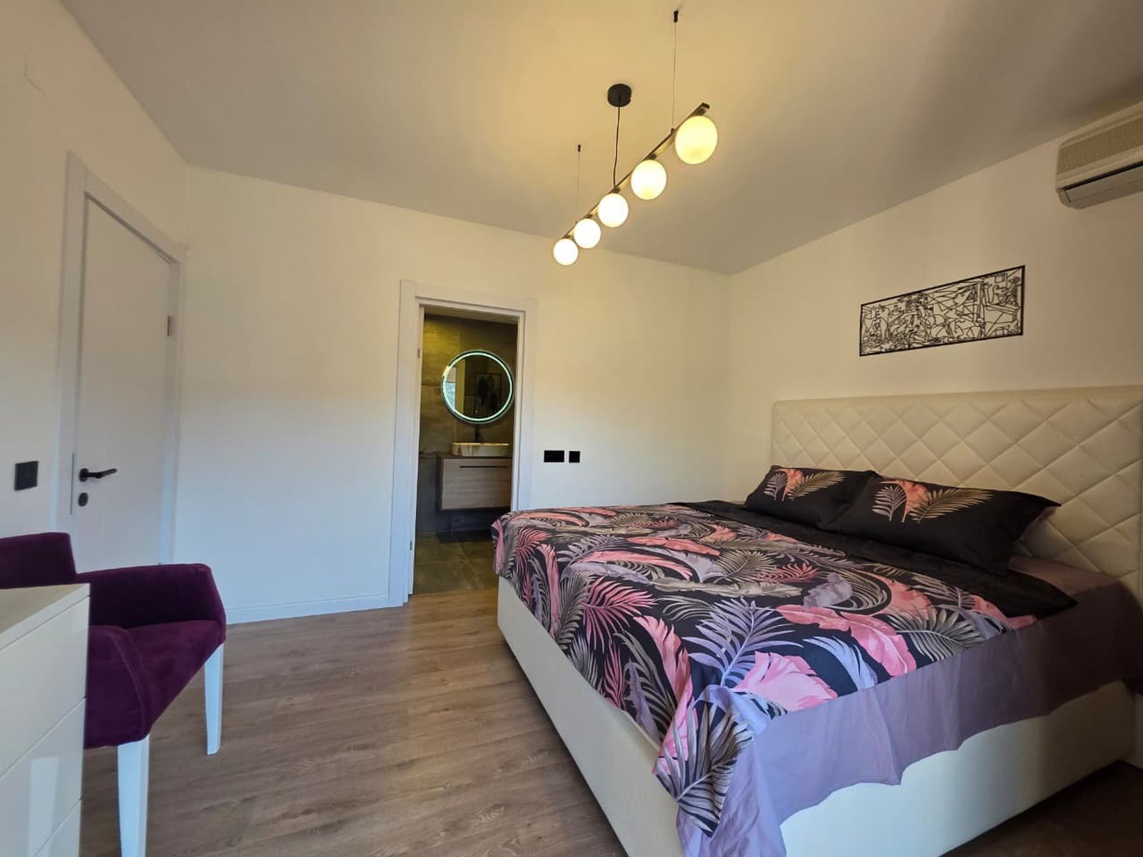Modern bedroom with a double bed and bathroom in an apartment in Bečići, Montenegro. Stylish interior, laminate flooring.