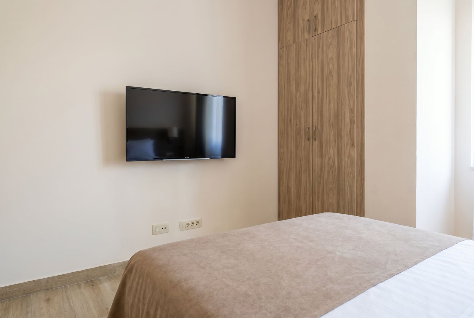 Modern bedroom in an apartment in Bečići, Montenegro: double bed, built-in wardrobe, and TV on the wall.