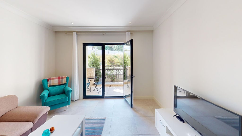 Bright living room in Lustica Bay apartments, Montenegro: soft furniture, terrace access, and a view of the greenery.