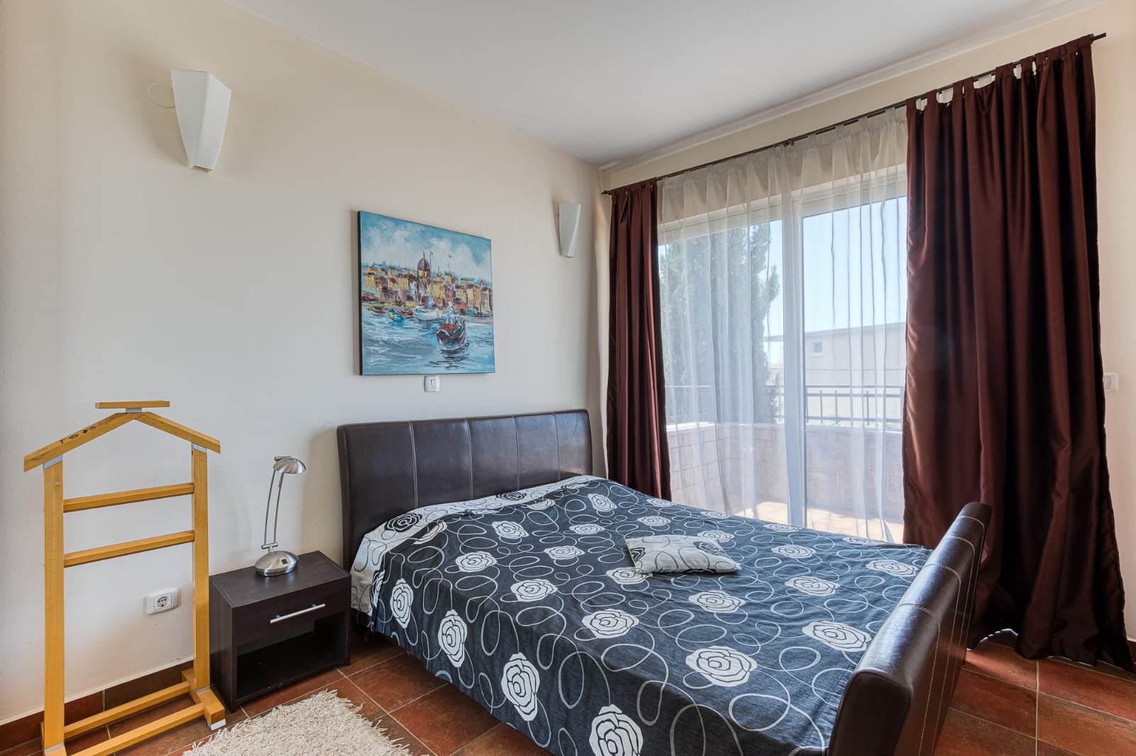 Bedroom with a double bed and terrace access in a villa in Becici, Montenegro. Cozy interior with a painting on the wall.