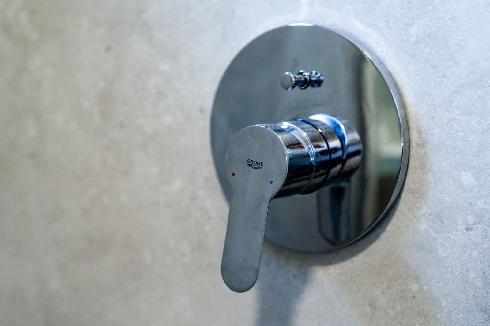 Chrome Grohe faucet in the bathroom of a residential complex in Budva, Montenegro. High-quality wall finish with light-colored tiles.