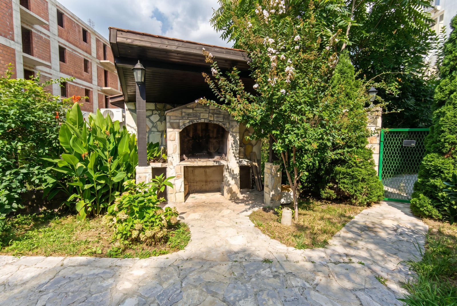 Barbecue area with a stone oven and garden in the private courtyard of an apartment in Budva, Montenegro.