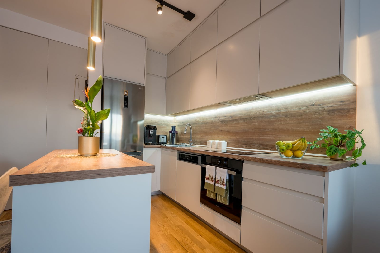 Modern kitchen in a Tivat apartment, Montenegro: white cabinetry, wooden countertop, and built-in appliances.