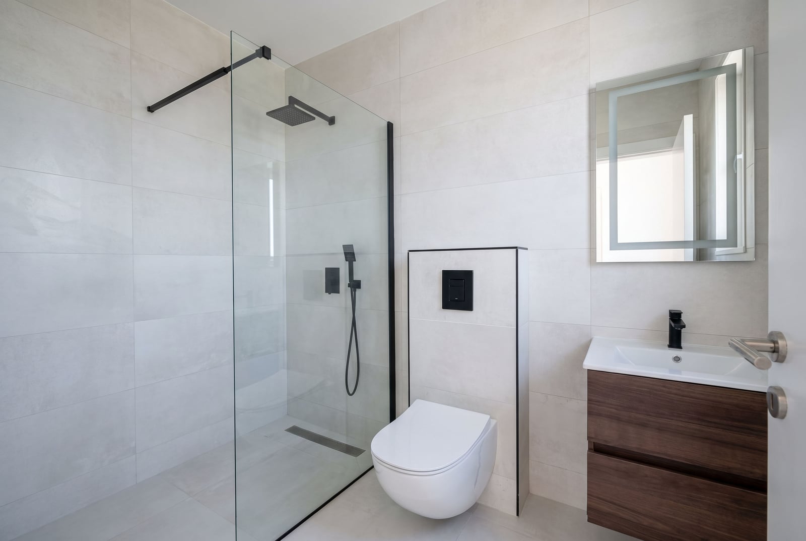 Modern bathroom featuring a glass-enclosed shower, wall-mounted toilet, and wooden vanity with sink.