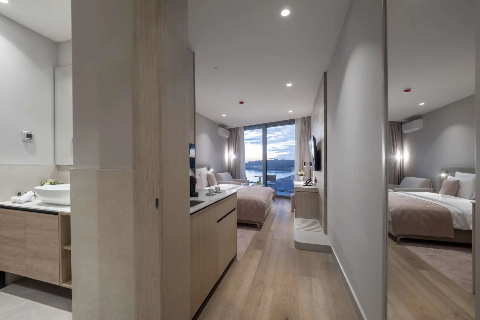 Hotel room with bed, water view, and open vanity area featuring a vessel sink.