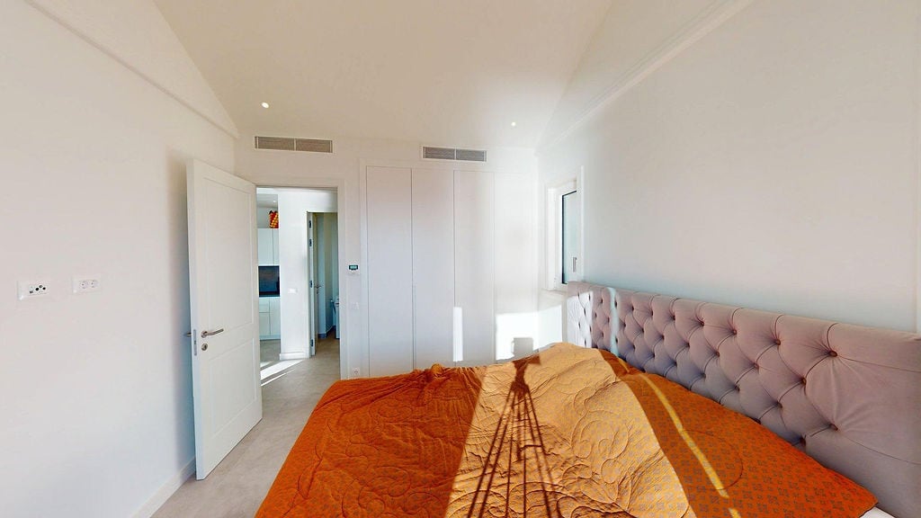 Bright bedroom with a bed and built-in wardrobe in the Lustica Bay apartments, Luštica, Montenegro.