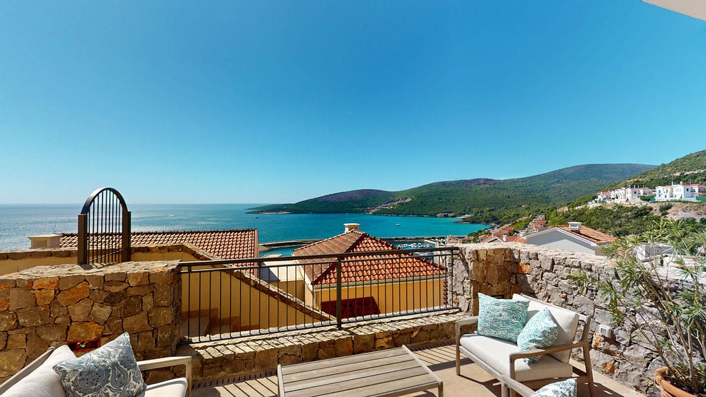 Terrace with garden furniture and panoramic sea and mountain views at the Luštica residential complex, Montenegro.