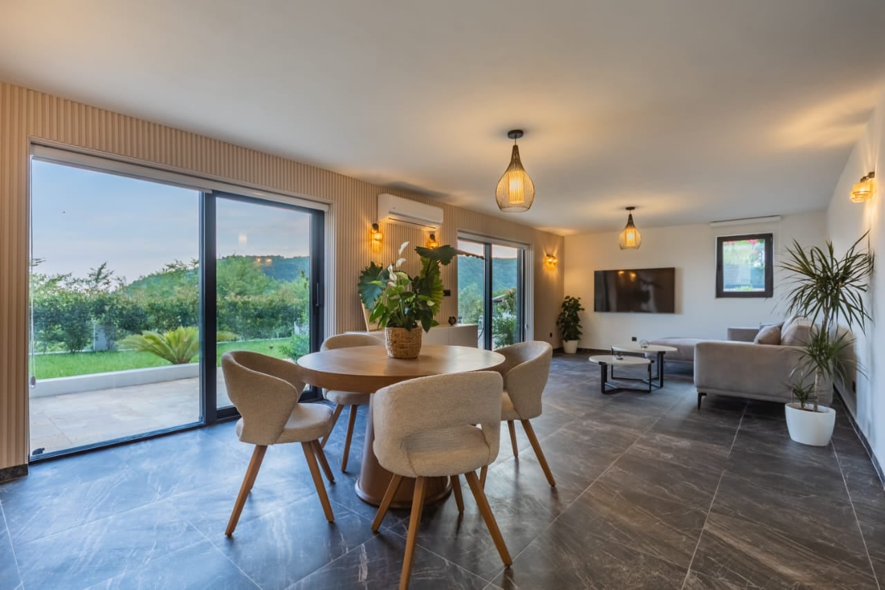 Modern living room with panoramic windows and garden access in a villa in Budva, Montenegro: stylish furniture and decor.