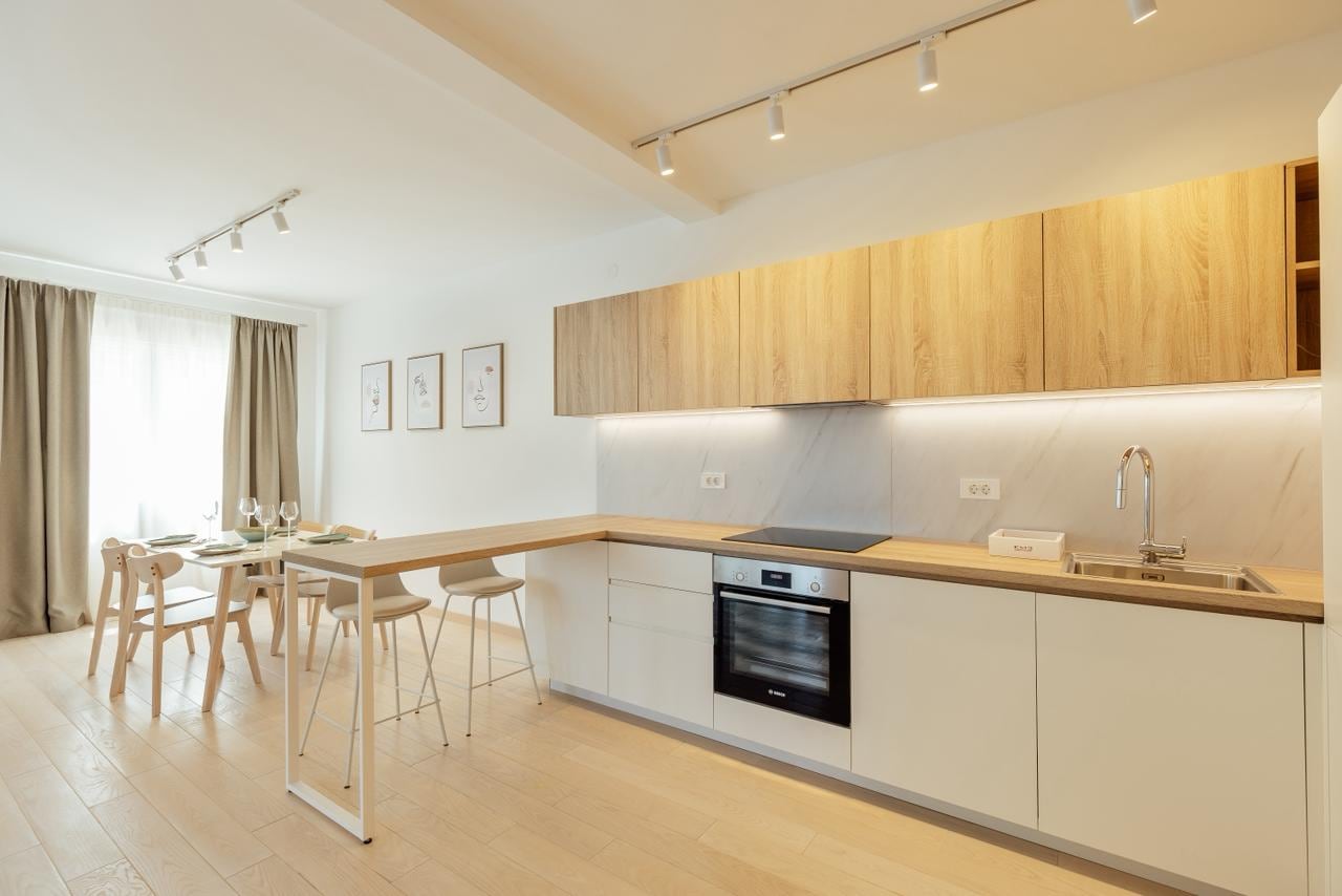 Modern kitchen-living room in an apartment, Igalo, Montenegro: light-colored furniture, breakfast bar, and dining area.