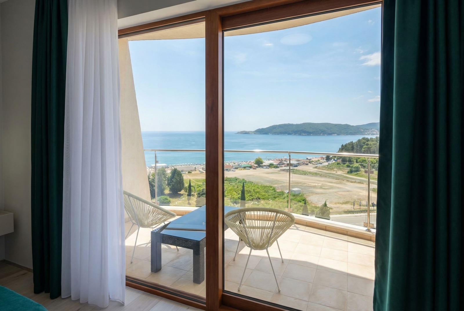 View from the apartment balcony in Bečići, Montenegro: panoramic windows, wicker furniture, and a direct view of the Adriatic Sea.